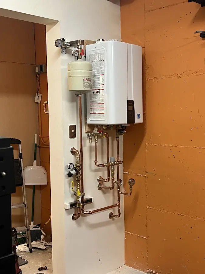Plumbing technician inspecting water heater connections in Alton